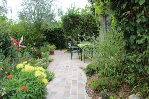 Allée et terrasse en grès metissay avec des massifs à l'anglaise